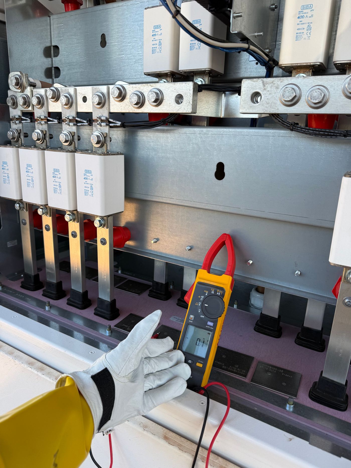 [ field photo: opened central inverter, measurements, DC distribution ]